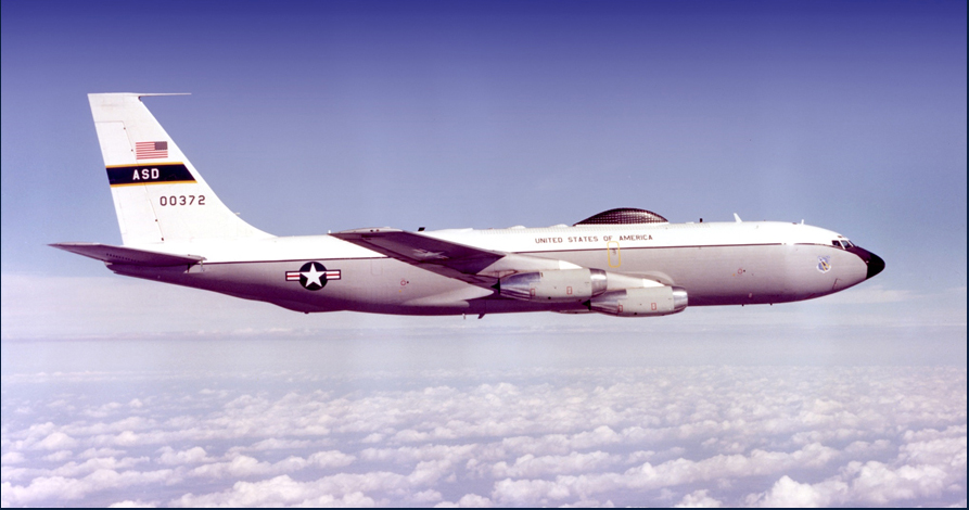 A photo of an aircraft mid-air above the clouds.