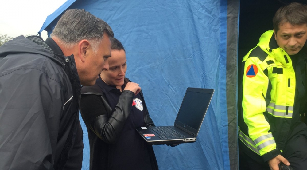 Two individuals look at a laptop screen.