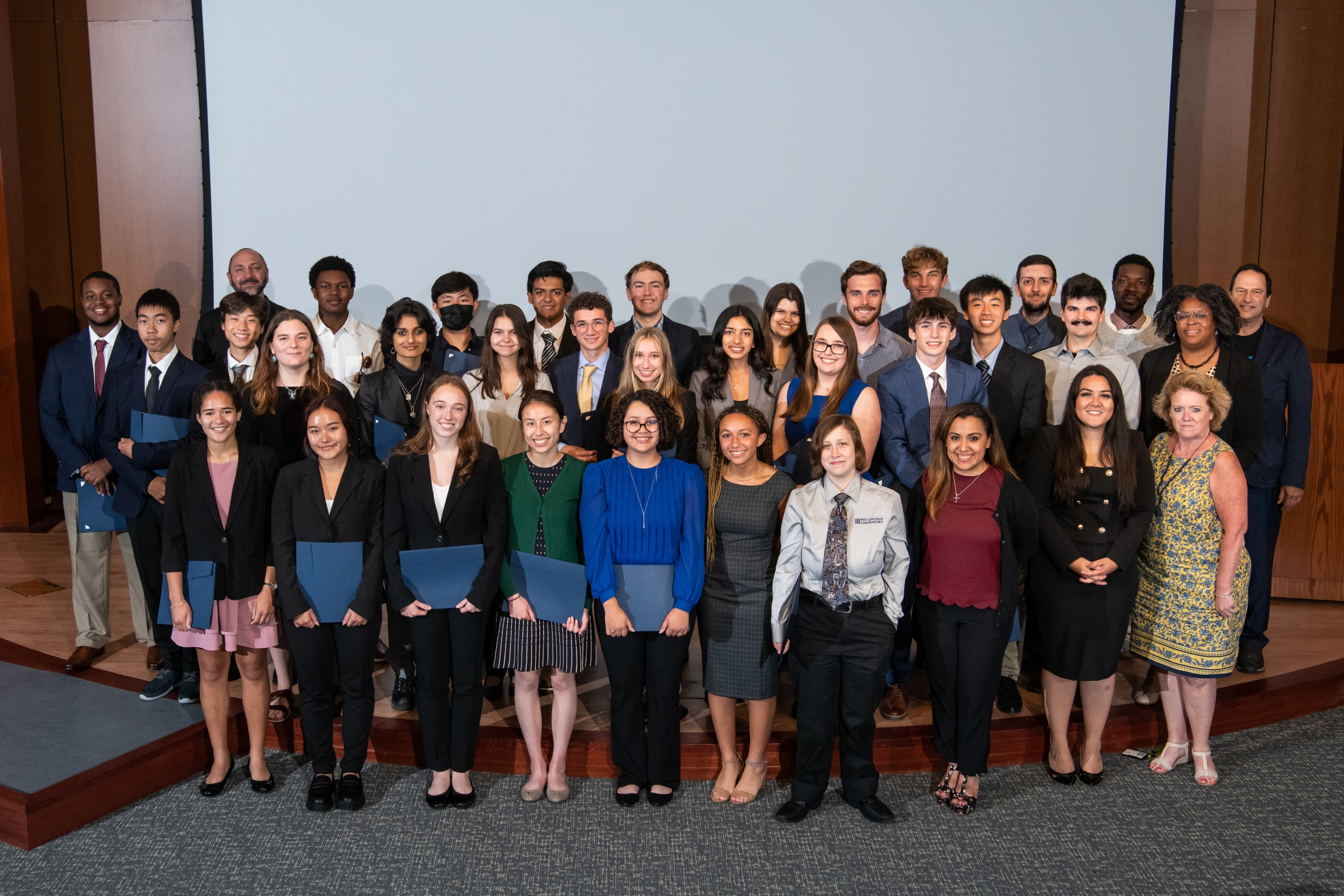 A group photo of about 25 people, mainly high school students, in the Lincoln Laboratory auditorium. 