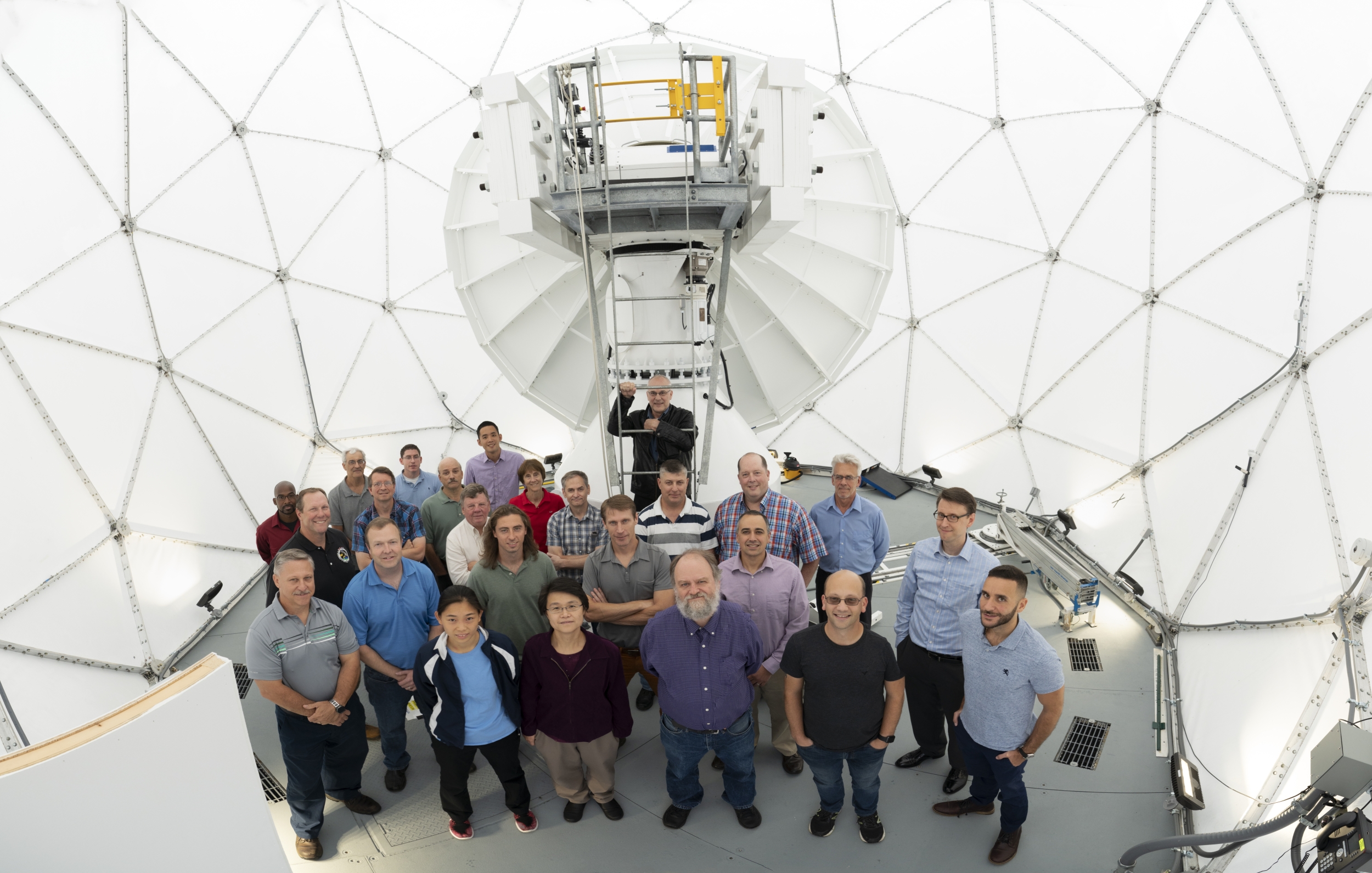 Twenty-five members part of the development team for the Multi-Band Test Terminal and Protected Anti-Jam Tactical SATCOM gather inside the antenna's radome.