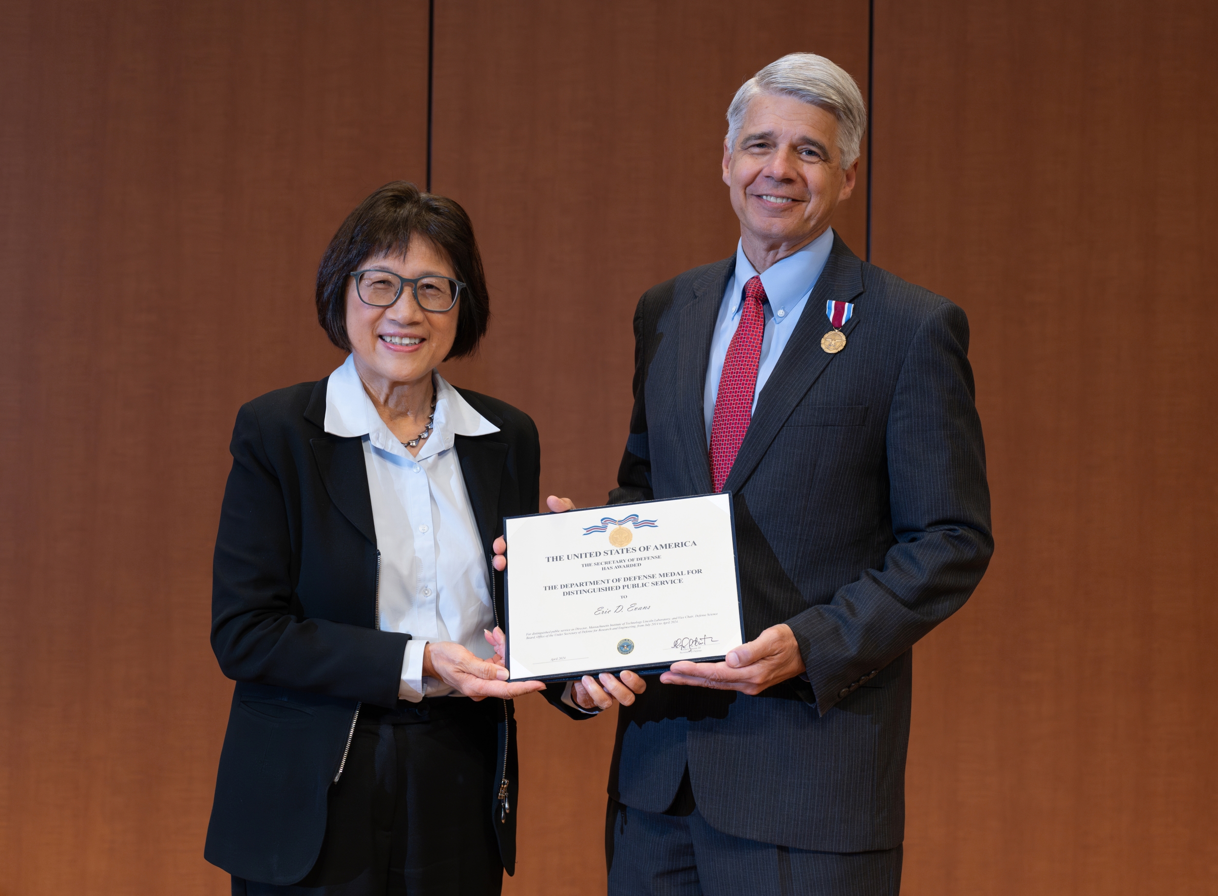 Heidi Shyu and Eric Evans stand side by side holding Evans' award for the Department of Defense Medal for Distinguished Public Service. Evans is pinned with the medal.