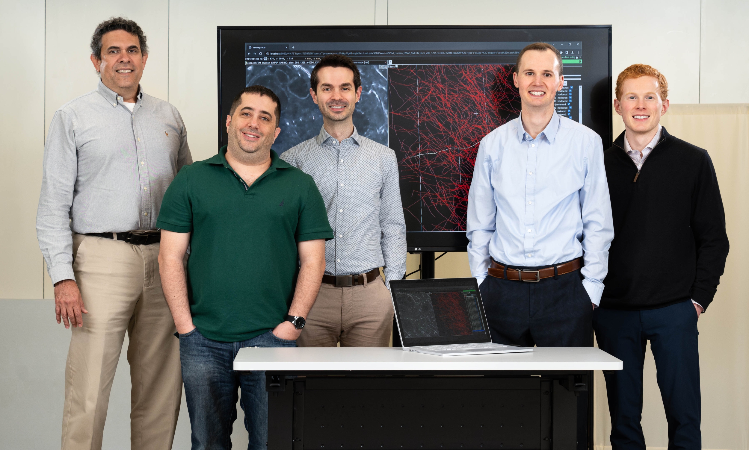 The NeuroTrALE team members stand in front of a projector showing a demo of the software. 