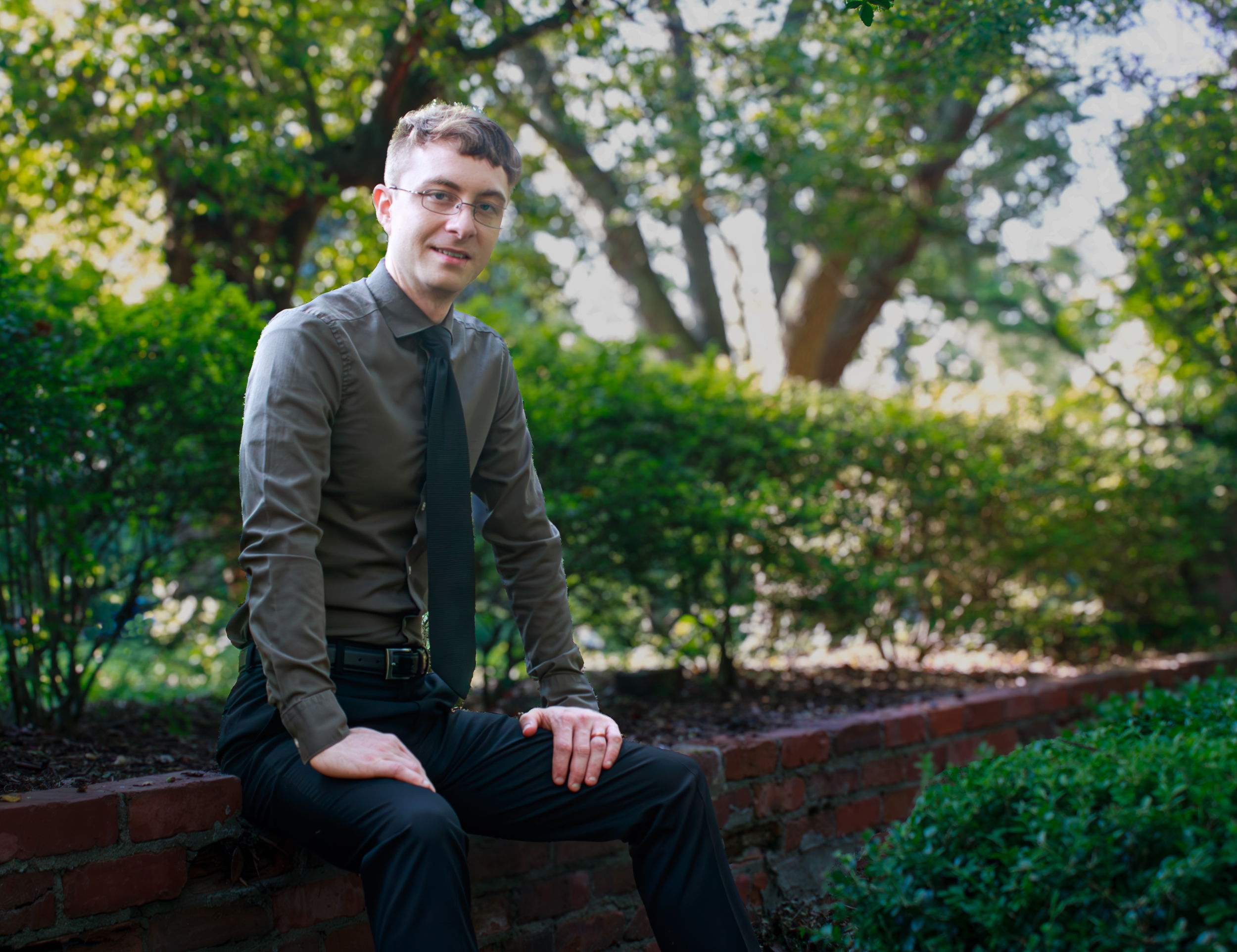 Connor Mathews sits outside on a brick wall 