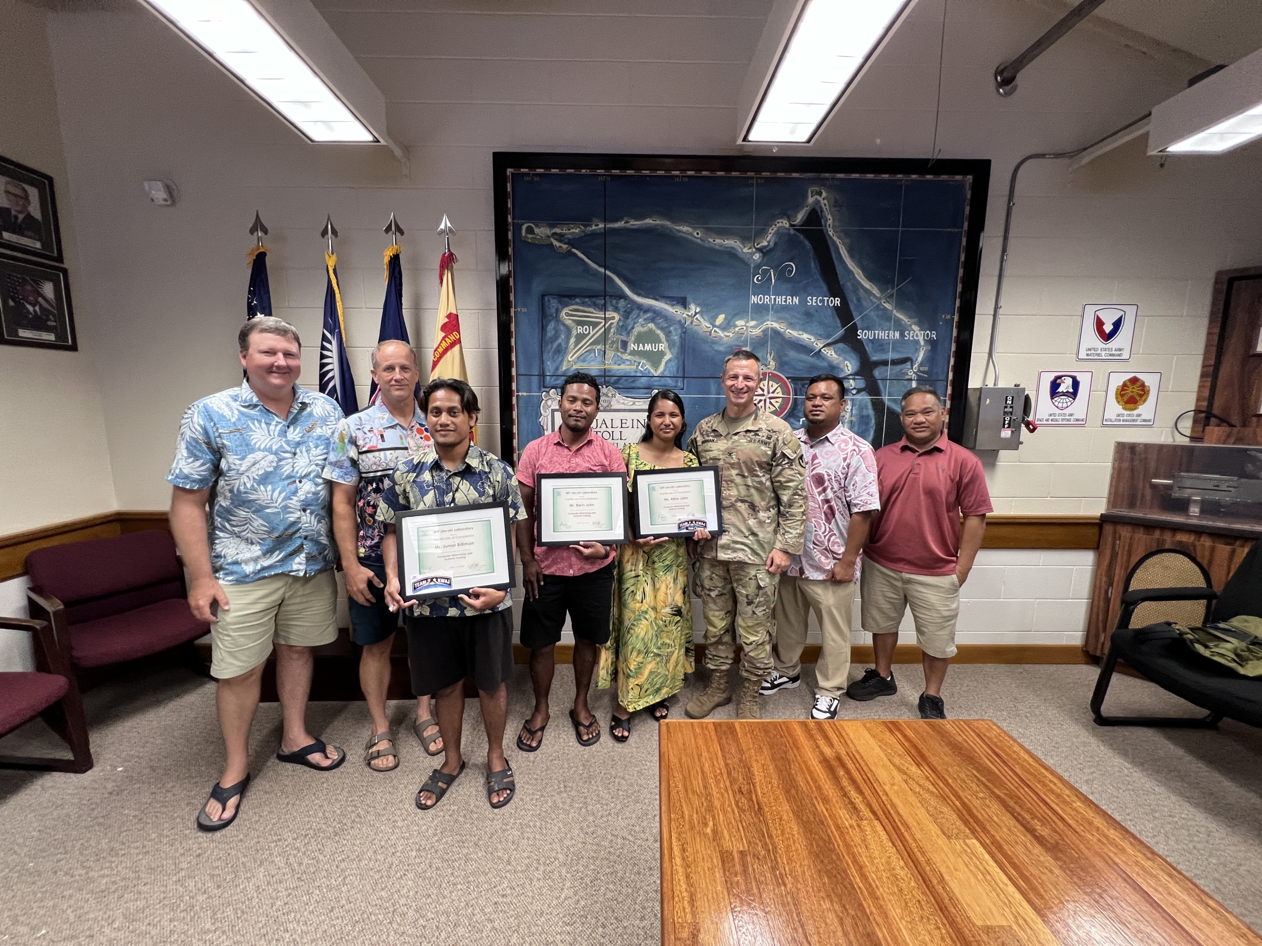 Eight individuals stand together, with three holding certificates. 