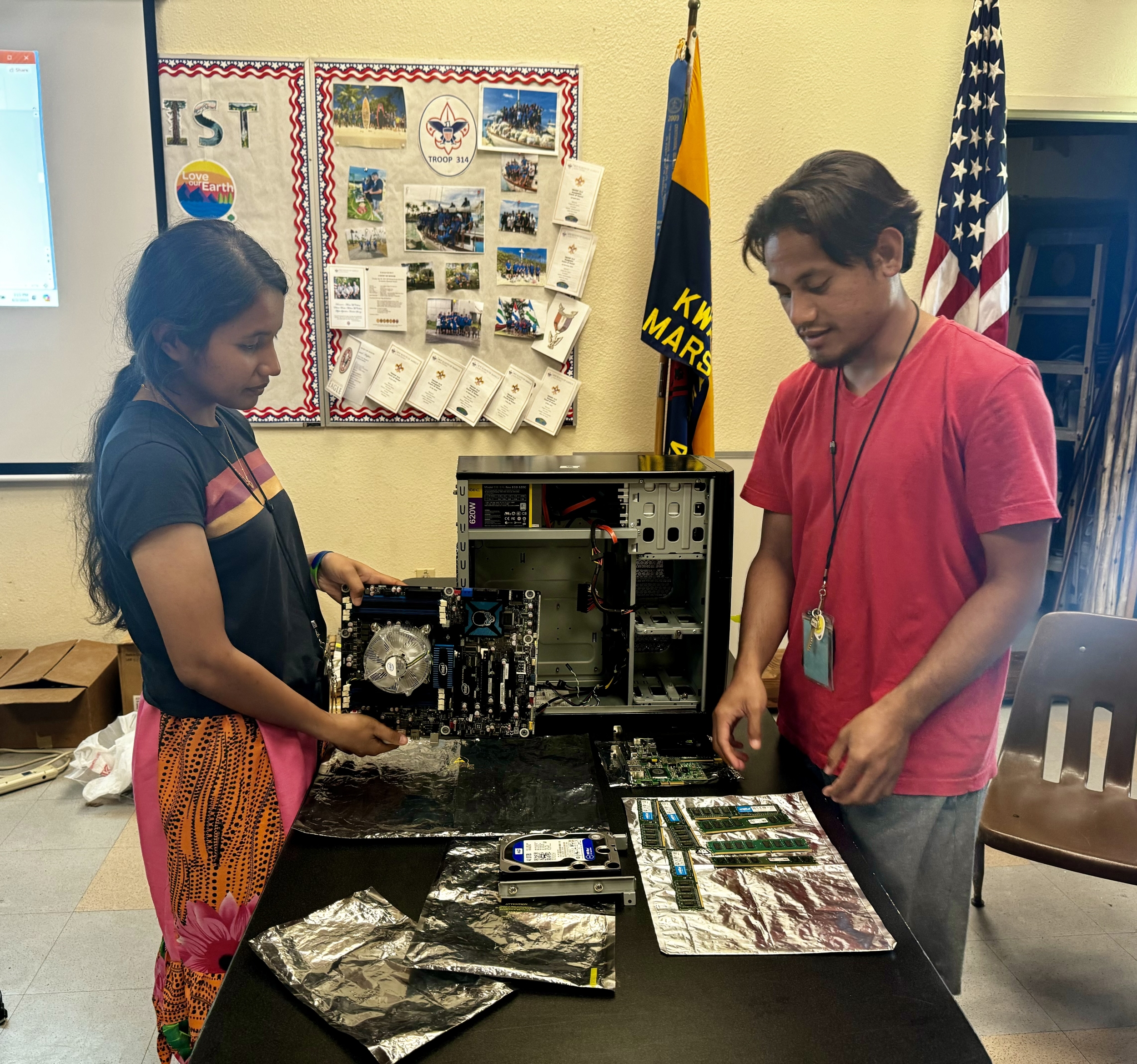 Two people disassemble a computer. 