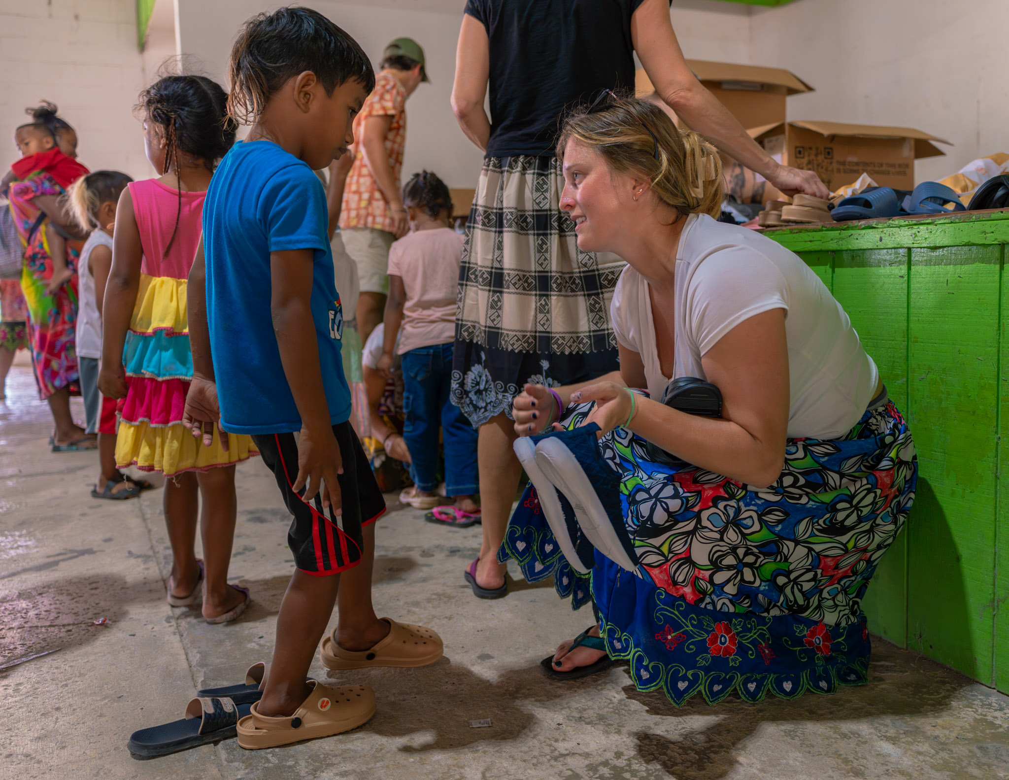 A woman helps a child try on shoes.