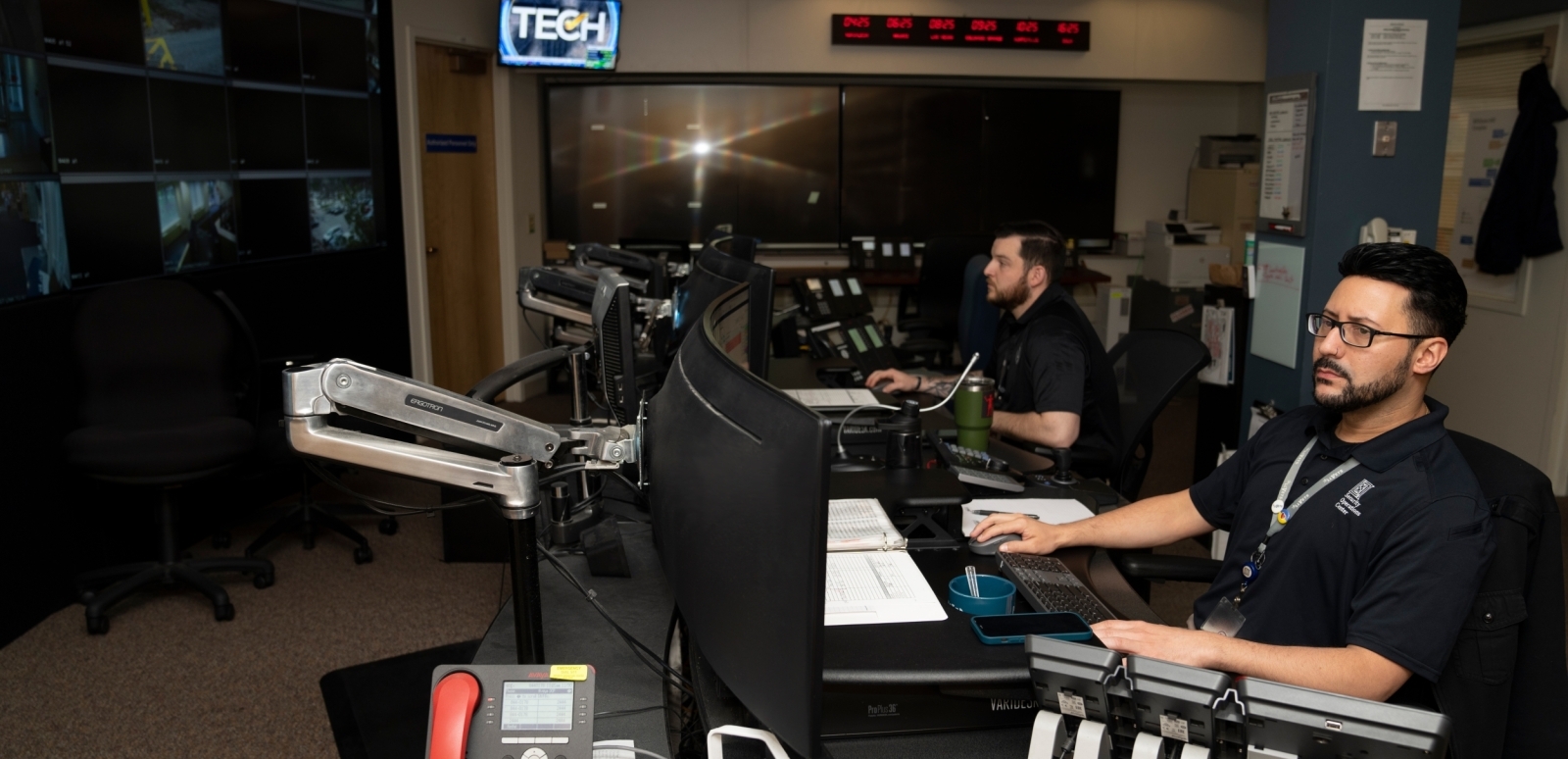 Two SSD employees work in front of several monitors.