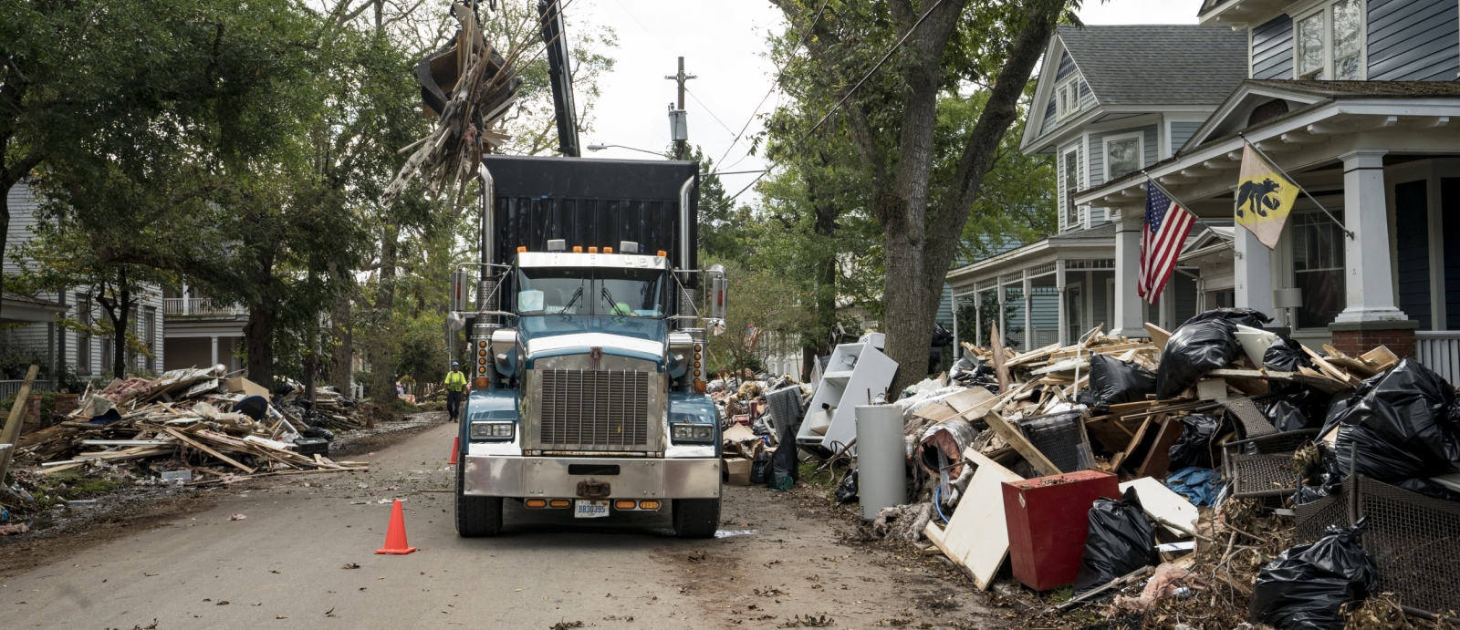 A photo of a large truck picking up debris lining a street