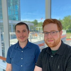 Two staff members pose in a hallway 