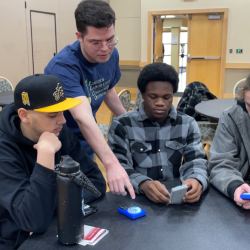 David Langus Rodriguez of Lincoln Laboratory helps three students use development boards.