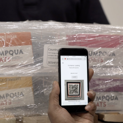 a photo of a person scanning a QR code, affixed to a small wrapped shipment of food, with a smartphone.