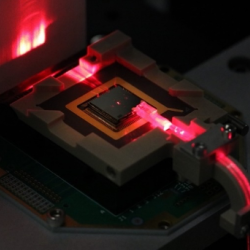 a small electronic chip is illuminated with red laser light. 