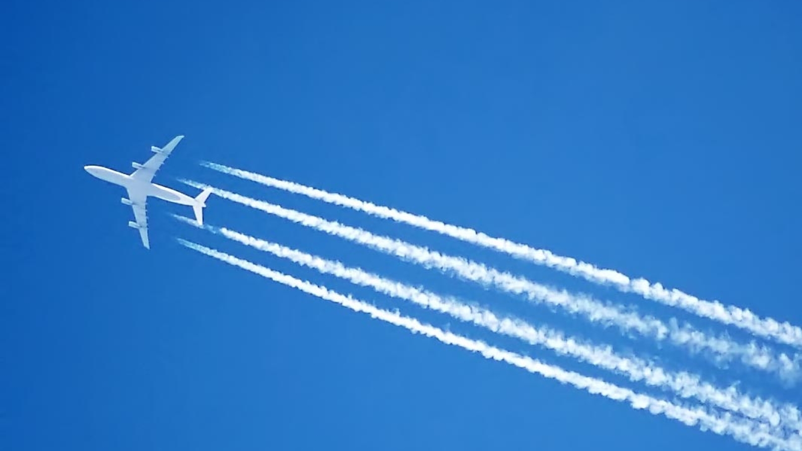 an image of a jet streaking across the sky, with contrails being left behind